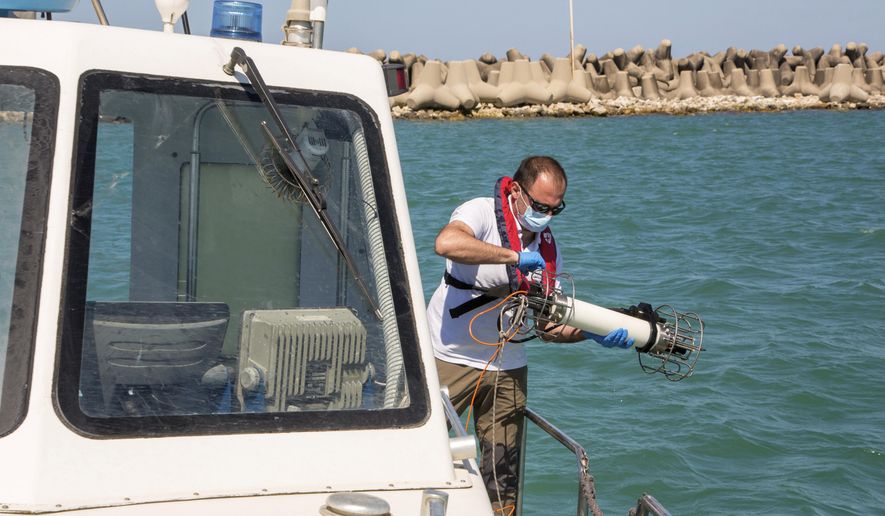 In this picture taken on Thursday, May 21, 2020, Italian Lazio region&#x27;s environmental agency biologist Salvatore De Bonis shows how they perform tests on sea water during an interview with The Associated Press on a Coast Guard boat off Fiumicino, near Rome. Preliminary results from a survey of seawater quality during Italy’s coronavirus lockdown indicate a sharp reduction in pollution from human and livestock waste in the seas off Rome. Authorities stressed it was too soon to give the lockdown sole credit for the change. (AP Photo/Domenico Stinellis)