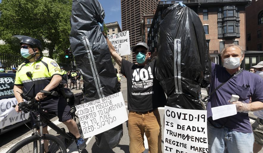 A counter-demonstrator holds up makeshift body bags while separated by police from a protest calling for the repeal of all government restrictions related to concern about the spread of COVID-19, Saturday, May 30, 2020, at the Statehouse, in Boston. (AP Photo/Michael Dwyer)