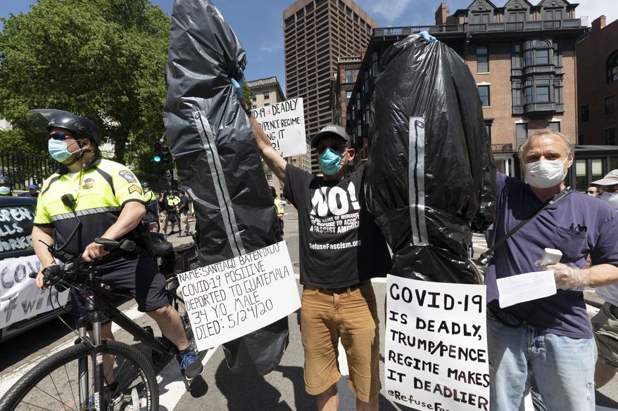 A counter-demonstrator holds up makeshift body bags while separated by police from a protest calling for the repeal of all government restrictions related to concern about the spread of COVID-19, Saturday, May 30, 2020, at the Statehouse, in Boston. (AP Photo/Michael Dwyer)