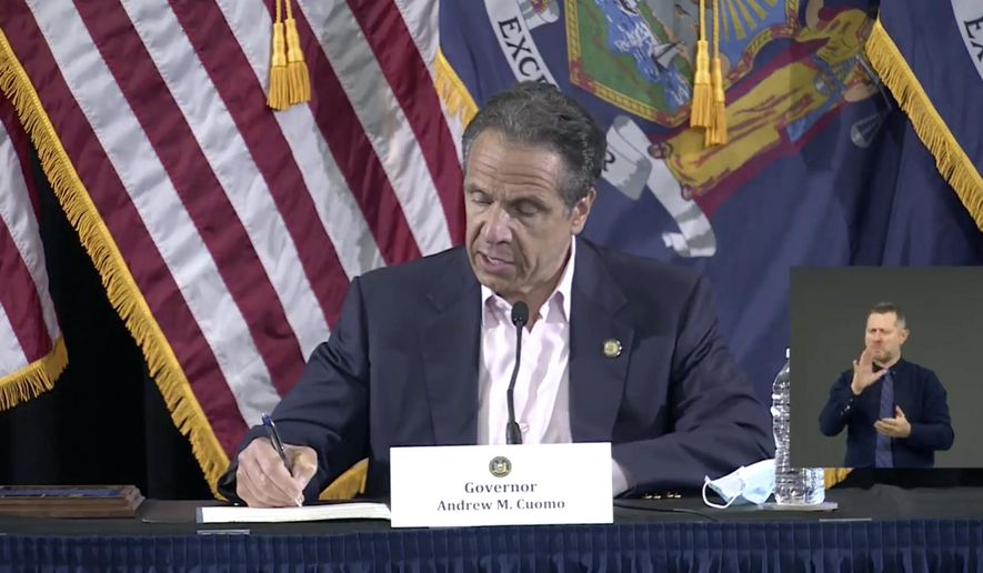 In this image made from video provided by the office of Gov. Andrew M. Cuomo, Gov. Cuomo signs a bill giving death benefits to the families of certain government workers who were killed by coronavirus, Saturday, May 30, 2020 in New York. (Office of Governor Andrew M. Cuomo via AP)