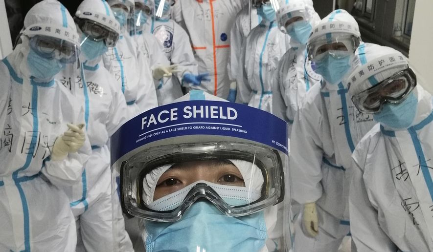 In this photo taken and released by Chinese nurse Zhang Dan, she poses for a photo with colleagues at the Wuhan Pulmonary Hospital in Wuhan in central China's Hubei province, Friday, April 4, 2020. Zhang was among the first to respond to the call for help in China's coronavirus epicenter. The 36-year-old nurse worked through grueling days, ministering to patients who needed assistance from breathing to merely eating. She struggled — but then, a little street dog helped her through. (Zhang Dan via AP)