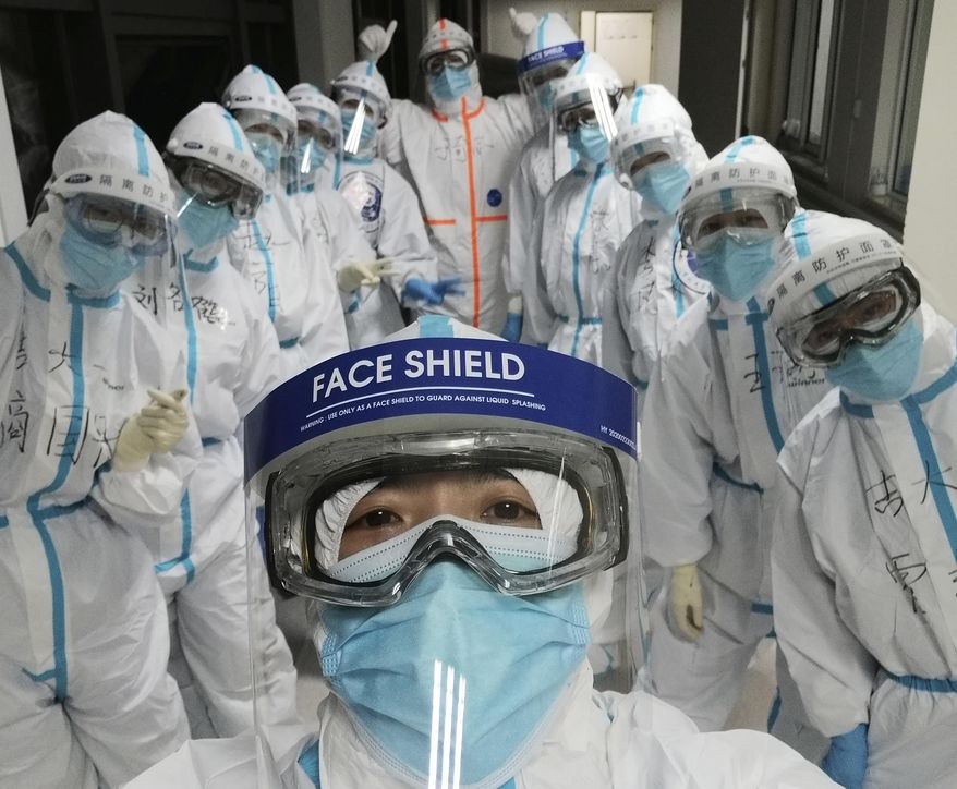 In this photo taken and released by Chinese nurse Zhang Dan, she poses for a photo with colleagues at the Wuhan Pulmonary Hospital in Wuhan in central China's Hubei province, Friday, April 4, 2020. Zhang was among the first to respond to the call for help in China's coronavirus epicenter. The 36-year-old nurse worked through grueling days, ministering to patients who needed assistance from breathing to merely eating. She struggled — but then, a little street dog helped her through. (Zhang Dan via AP)