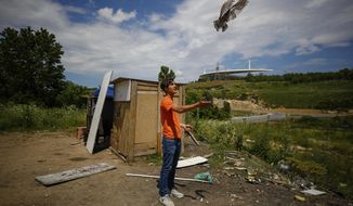 A local resident trains a pigeon at an area, near the Ataturk Olympic Stadium, background, in Istanbul, Saturday, May 30, 2020. The UEFA Champions League final soccer match was scheduled to be hosted at Ataturk Olympic Stadium May 30 but is postponed because of the coronavirus pandemic and a new date for the final has yet to be announced amid the ongoing COVID-19 crisis.(AP Photo/Emrah Gurel)