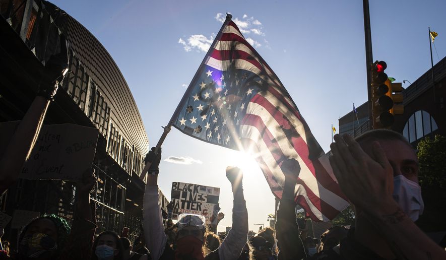 A man holds a U.S. flag upside down, a sign of distress, as protesters march down the street during a solidarity rally for George Floyd, Sunday, May 31, 2020, in the Brooklyn borough of New York. Protests were held throughout the city over the death of Floyd, a black man in police custody in Minneapolis who died after being restrained by police officers on Memorial Day. (AP Photo/Wong Maye-E)