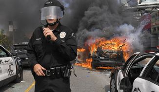 Los Angeles Police Department commander Cory Palka stands among several destroyed police cars as one explodes while on fire during a protest over the death of George Floyd, Saturday, May 30, 2020, in Los Angeles. Floyd died in police custody on Memorial Day in Minneapolis. (AP Photo/Mark J. Terrill)
