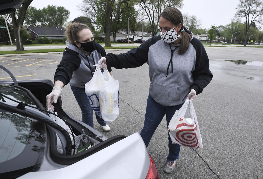 Home base supervisor Connie Graska, left, of the Addison Children's Center and the Metropolitan Family Services, loads up diapers and pasta with the help of Dana Trummer, site supervisor, into the car of a person's family in need of these staple items, amid the coronavirus pandemic, May 19, 2020, in Addison, Ill. (Mark Welsh/Daily Herald via AP)