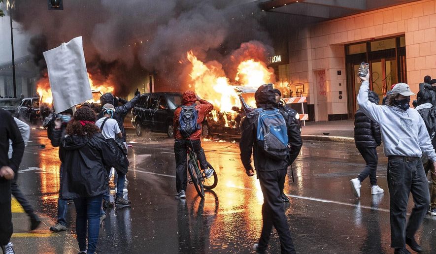 People set fire to vehicles during a protest, Saturday, May 30, 12020 in Seattle. Protests were held throughout the country over the death of George Floyd, a black man who died after being restrained by Minneapolis police officers on May 25. (Dean Rutz/The Seattle Times via AP)
