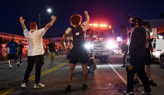 Demonstrators block the path of a Los Angeles Fire Department truck during a public disturbance on Melrose Avenue, Saturday, May 30, 2020, in Los Angeles. Protests were held in U.S. cities over the death of George Floyd, a black man who died after being restrained by Minneapolis police officers on May 25. (AP Photo/Chris Pizzello)