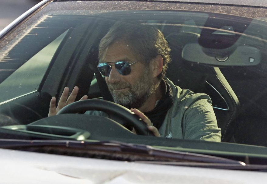 Liverpool soccer team manager Jurgen Klopp waves as he arrives at the club's Melwood training ground after the English Premier League announced players can return to training in small groups as the coronavirus lockdown is eased Wednesday May 20, 2020. (Peter Byrne/PA via AP)