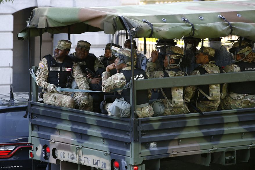 Members of the District of Columbia National Guard ride in a vehicle on West Executive Avenue next to the White House, Monday, June 1, 2020, in Washington, as protesters over the death of George Floyd, a black man who died in police custody in Minneapolis, demonstrate nearby. (AP Photo/Patrick Semansky)