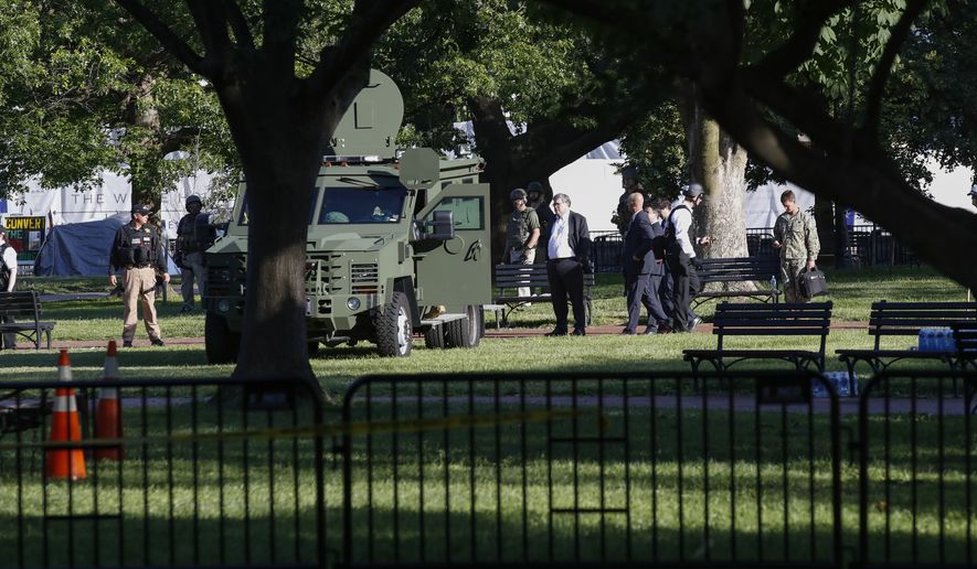 Attorney General William Barr, center, stands in Lafayette Park across from the White House as demonstrators gather to protest the death of George Floyd, Monday, June 1, 2020, in Washington. Floyd died after being restrained by Minneapolis police officers. (AP Photo/Alex Brandon)