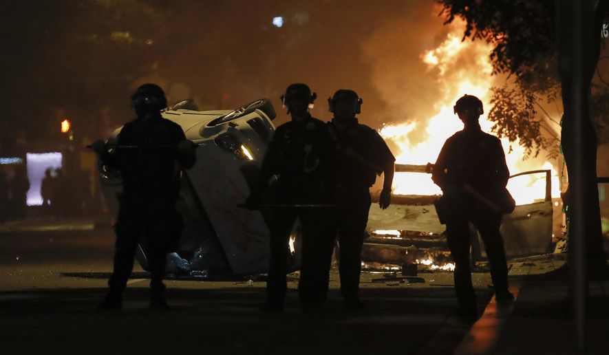 Police stand near a overturned vehicle and a fire as demonstrators protest the death of George Floyd, Sunday, May 31, 2020, near the White House in Washington. Floyd died after being restrained by Minneapolis police officers (AP Photo/Alex Brandon)