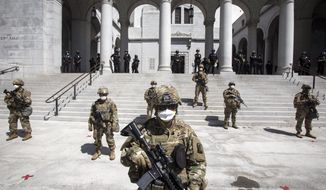 Members of California National Guard stand guard outside the City Hall, Sunday, May 31, 2020, in Los Angeles. The National Guard is patrolling Los Angeles as the city begins cleaning up following a night of violent protests against police brutality. The demonstration Saturday night was sparked by the death of George Floyd, a black man who was killed in police custody in Minneapolis on May 25. (AP Photo/Ringo H.W. Chiu)