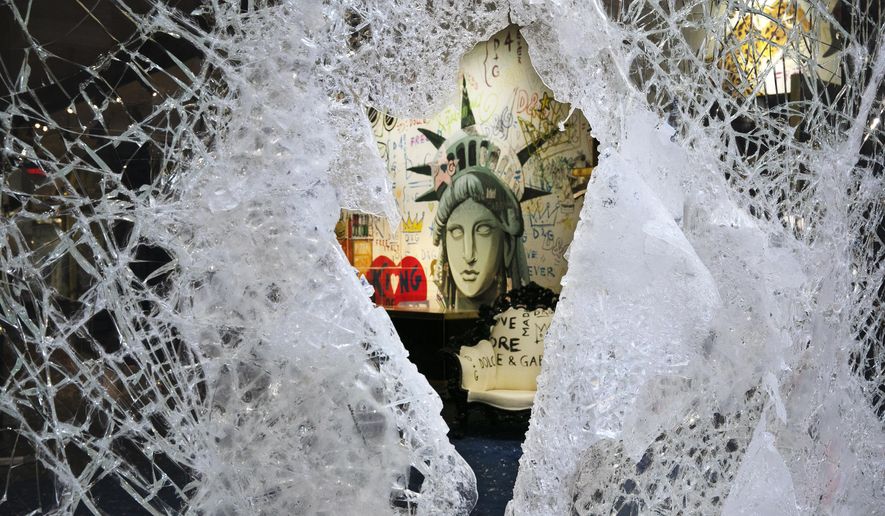 A Statue of Liberty painting is seen through a smashed Dolce and Gabbana store window, Monday, June 1, 2020, in the SoHo neighbourhood of New York. Protesters broke into the store Sunday night in reaction to George Floyd's death while in police custody on May 25 in Minneapolis. (AP Photo/Mark Lennihan)
