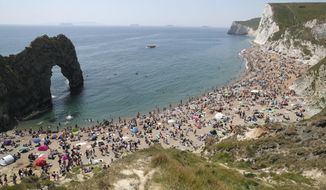 People on the beach at Durdle Door, as the public are being reminded to practice social distancing following the relaxation of coronavirus lockdown restrictions, near Lulworth in Dorset, England, Saturday, May 30, 2020.  (Andrew Matthews/PA via AP)