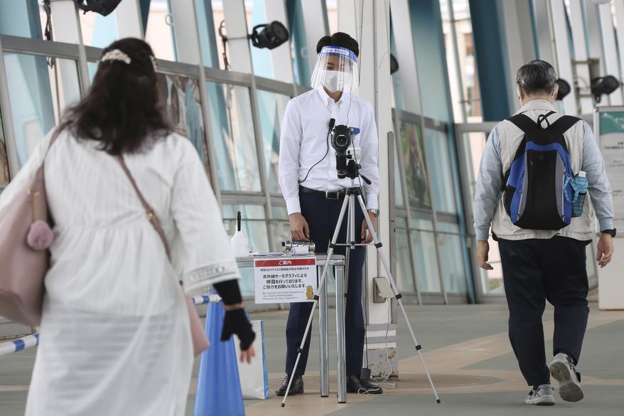 Visitors walk past a thermography camera monitors as the Hakkeijima Sea Paradise amusement park opens after a two-month closure due to the preventative measures to help curb the spread of the coronavirus in Yokohama near Tokyo, Monday, June 1, 2020. (AP Photo/Koji Sasahara)
