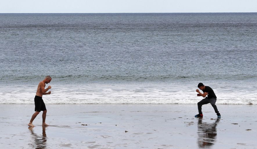 MMA fighter Chris Caterino, left, and boxer Jimmy Laboy train at a social distance along the shore of Salisbury Beach, Monday, June 1, 2020, in Salisbury, Mass. Beachgoers are restricted to keep more than six feet apart due to the COVID-19 outbreak. (AP Photo/Charles Krupa)