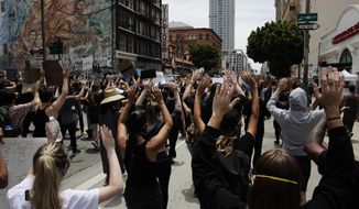 Demonstrators march with their arms raised in Los Angeles, Tuesday, June 2, 2020, in a protest over the death of George Floyd, who died after being restrained by Minneapolis police officers on May 25. (AP Photo/Jae C. Hong)