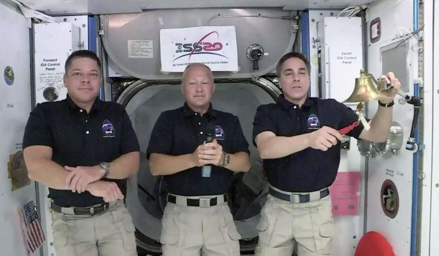 CORRECTS TO NASDAQ, NOT NEW YORK STOCK EXCHANGE - In this image from video made available by NASA, astronaut Chris Cassidy, right, rings the opening bell of the Nasdaq Stock Exchange accompanied by fellow astronauts Robert L. Behnken, left, and Doug Hurley in the International Space Station on Tuesday, June 2, 2020. (NASA via AP)