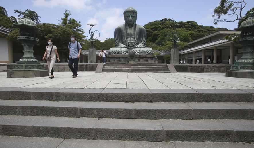 People wearing face masks to protect against the spread of the new coronavirus visit The Great Buddha statue at Kotoku-in Temple in Kamakura, near Tokyo Tuesday, June 2, 2020. Japanese Prime Minister Shinzo Abe announced the lift of a coronavirus state of emergency from Tokyo and four other remaining areas last week, ending the restrictions nationwide as businesses begin to reopen. (AP Photo/Koji Sasahara)