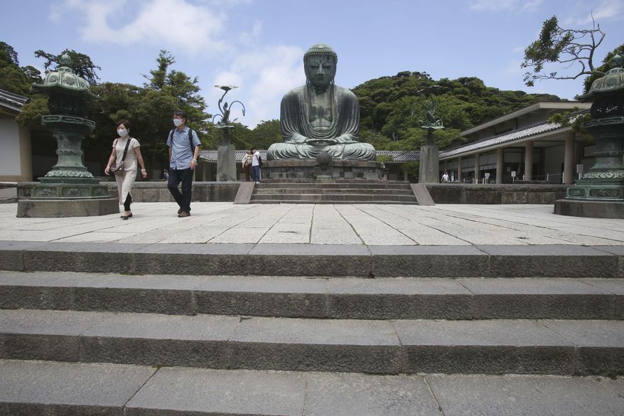 People wearing face masks to protect against the spread of the new coronavirus visit The Great Buddha statue at Kotoku-in Temple in Kamakura, near Tokyo Tuesday, June 2, 2020. Japanese Prime Minister Shinzo Abe announced the lift of a coronavirus state of emergency from Tokyo and four other remaining areas last week, ending the restrictions nationwide as businesses begin to reopen. (AP Photo/Koji Sasahara)