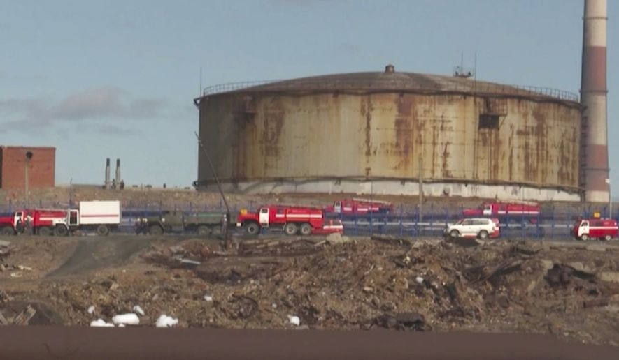 In this image taken from video provided by the RU-RTR Russian television on Wednesday, June 3, 2020, Russian Emergency Situations Ministry trucks work at the scene of an oil spill at a power plant in an outlying section of the city of Norilsk, 2900 kilometers (1800 miles) northeast of Moscow, Russia. Russian President Vladimir Putin has declared a state of emergency in a region of Siberia after an estimated 20,000 tons of diesel fuel spilled from a power plant storage facility and fouled waterways. (RU-RTR Russian Television via AP)