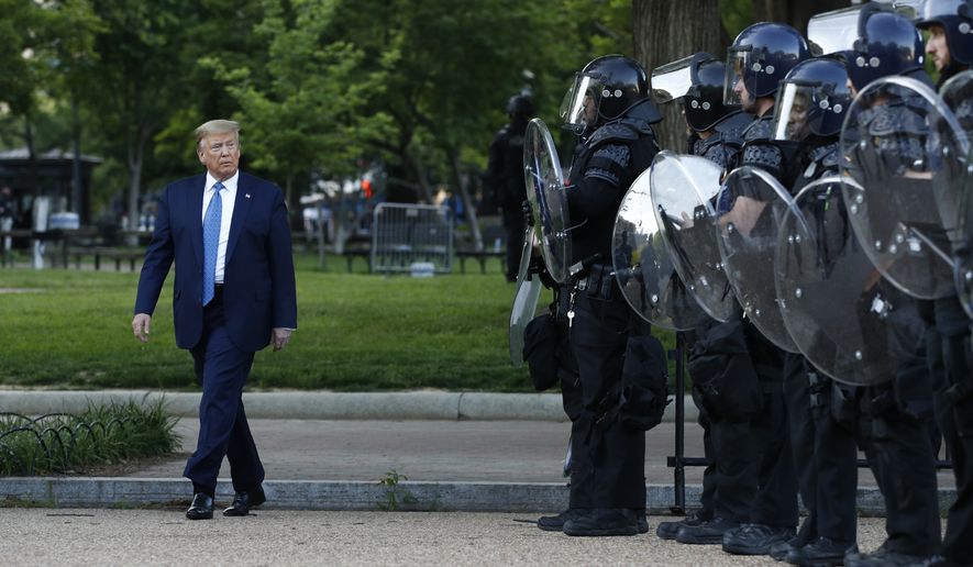 In this Monday, June 1, 2020, file photo, President Donald Trump walks past police in Lafayette Park after visiting outside St. John&#39;s Church across from the White House in Washington. Part of the church was set on fire during protests on Sunday night. (AP Photo/Patrick Semansky, File)