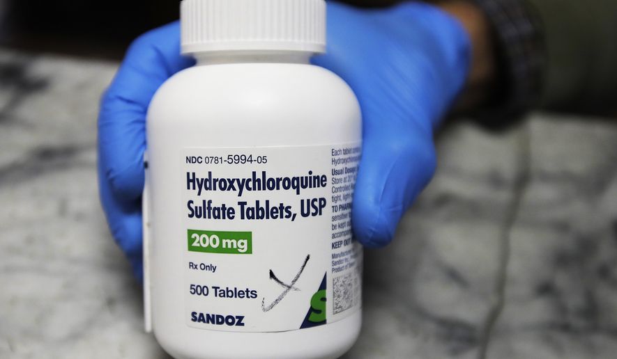 In this April 6, 2020, photo, a pharmacist holds a bottle of the drug hydroxychloroquine in Oakland, Calif. (AP Photo/Ben Margot) **FILE**