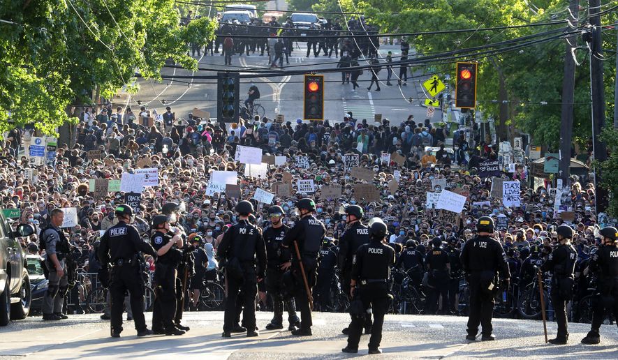 A sea of peaceful protesters are kept back from the Seattle Police Department&#x27;s East Precinct on Capitol Hill, by a two-block buffer of officers and gates, seen in the foreground, Monday, June 1, 2020, in Seattle, as demonstrations continue, sparked by the death of George Floyd in Minneapolis. (Ken Lambert/The Seattle Times via AP)