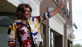 Mayor-elect Ella Jones waves to a supporter passing by while posing for a photo Wednesday, June 3, 2020, in Ferguson, Mo. Jones, currently a city council member who was elected mayor on Tuesday, will become the first black and first woman mayor of the city thrust into the national spotlight after the death of Michael Brown in 2014. (AP Photo/Jeff Roberson)