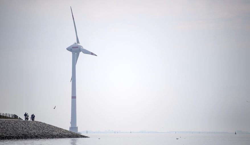 Cyclists ride along the dyke in Emden, Germany, Wednesday, June 3, 2020. The German government wants to increase offshore wind power capacity five-fold by 2040 as part of its plan to wean the country off fossil fuels. Cabinet on Wednesday agreed a bill that would set a goal of 40 Gigawatts of installed offshore wind power capacity in 20 years, from about 7.5 Gigawatts at present. It also raised the target for 2030 from 15 Gigawatts to 20. (Sina Schuldt/dpa via AP)
