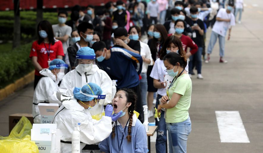FILE - In this May 15, 2020 file photo, people line up for medical workers to take swabs for the coronavirus test at a large factory in Wuhan in central China&#x27;s Hubei province. The Chinese city of Wuhan has tested nearly 10-million people for the new coronavirus in an unprecedented 19-day campaign to check an entire city. (Chinatopix Via AP)