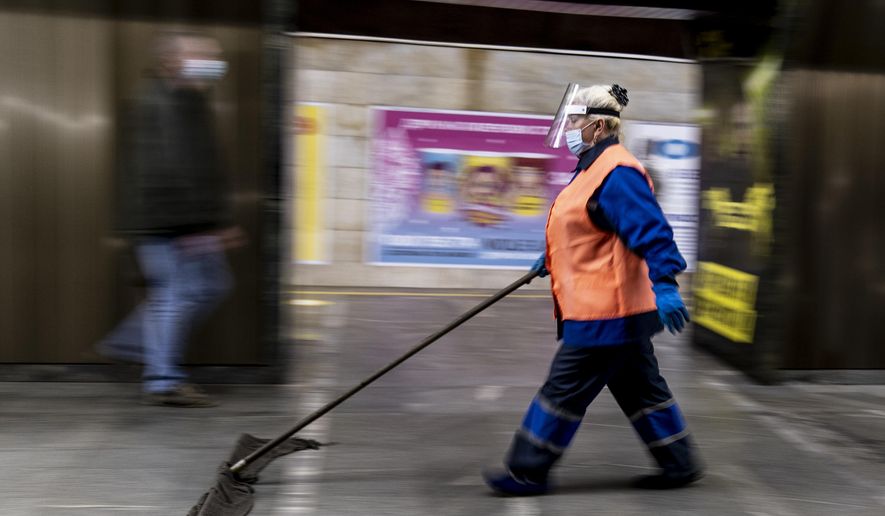An employee wearing face masks and gloves to protect against the COVID-19 coronavirus cleans a floor at a subway station in Kyiv, Ukraine on Monday, June 1, 2020. Ukraine continued to ease its coronavirus restrictions Monday, lifting a ban on intercity travel and allowing gyms and swimming pools to reopen. (AP Photo/Evgeniy Maloletka)