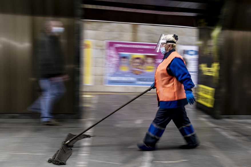 An employee wearing face masks and gloves to protect against the COVID-19 coronavirus cleans a floor at a subway station in Kyiv, Ukraine on Monday, June 1, 2020. Ukraine continued to ease its coronavirus restrictions Monday, lifting a ban on intercity travel and allowing gyms and swimming pools to reopen. (AP Photo/Evgeniy Maloletka)