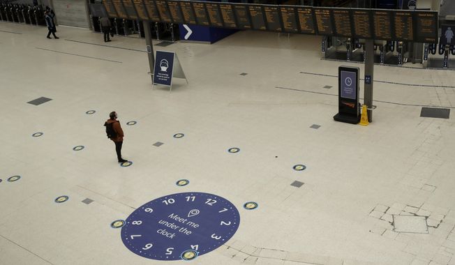 Social distancing guidelines on the floor by train departure information screens to help stop the spread of coronavirus in Waterloo station, London, Thursday, June 4, 2020. Waterloo station, which is wide recognised as the busiest train station in Britain, is still much quieter than normal as most commuters are working from home and not commuting into central London offices. (AP Photo/Matt Dunham)