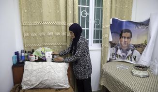 In this Wednesday, June 3, 2020 photo, Rana, mother of Eyad Hallaq, arranges his room in their home in East Jerusalem&#39;s Wadi Joz. Early Saturday, Hallaq, a 32-year-old Palestinian with severe autism, was chased by Israeli border police forces into a nook in Jerusalem&#39;s Old City and fatally shot as he cowered next to a garbage bin after apparently being mistaken as an attacker. He was just a few meters from his beloved Elwyn El Quds school. (AP Photo/Mahmoud Illean)