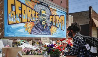 Malaysia Hammond, 19, places flowers at a memorial mural for George Floyd at the corner of Chicago Avenue and 38th Street, Sunday, May 31, 2020, in Minneapolis. Protests continued following the death of George Floyd, who died after being restrained by Minneapolis police officers on Memorial Day. (AP Photo/John Minchillo)