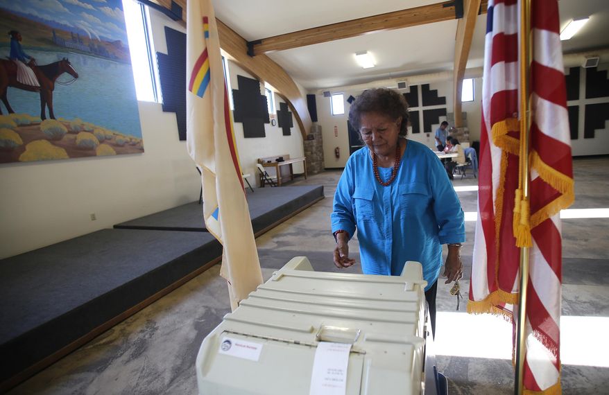 FILE - In this July 21, 2015, file photo, Martha Johnson turns in her ballot at the Nenahnezad Chapter House in Fruitland, N.M., during the Navajo Nation's referendum election. Native American voting rights advocates are cautioning against states moving to mail-in ballots without opportunities for tribal members to vote safely in person. The Native American Rights Fund released a wide-ranging report on voting rights Thursday, June 4, 2020. In it, the group outlined the challenges that could arise as states move to rely more heavily on mail-in ballots. (Jon Austria/The Daily Times via AP, File)