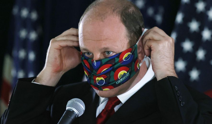 FILE—In this Thursday, May 28, 2020, file photograph, Colorado Governor Jared Polis puts on his face mask after a news conference about the state's efforts against the new coronavirus in Denver. During a news conference Tuesday, June 2, 2020, Polis said that the state is adding more than 800 new contact tracers to Colorado's coronavirus testing effort. (AP Photo/David Zalubowski, File)