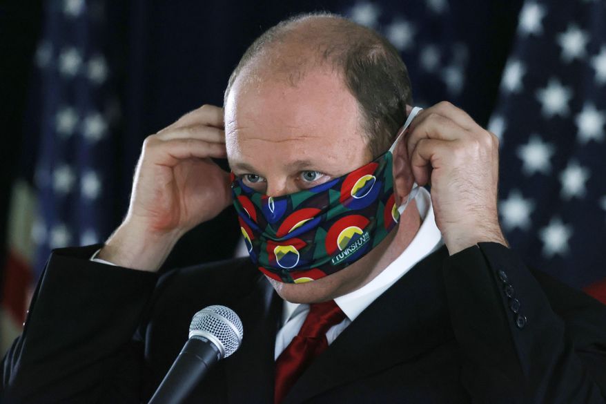 FILE—In this Thursday, May 28, 2020, file photograph, Colorado Governor Jared Polis puts on his face mask after a news conference about the state's efforts against the new coronavirus in Denver. During a news conference Tuesday, June 2, 2020, Polis said that the state is adding more than 800 new contact tracers to Colorado's coronavirus testing effort. (AP Photo/David Zalubowski, File)