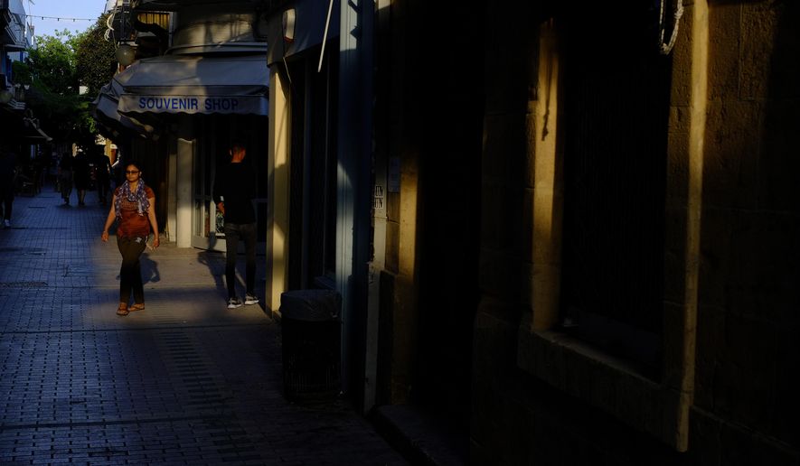 A woman walks past a closed souvenir shop in central capital Nicosia, Cyprus, Wednesday, June 3, 2020. Health Minister Constantinos Ioannou said the third phase of the country's gradual rollback of restrictions will be completed by June 24 instead of July 14. (AP Photo/Petros Karadjias)