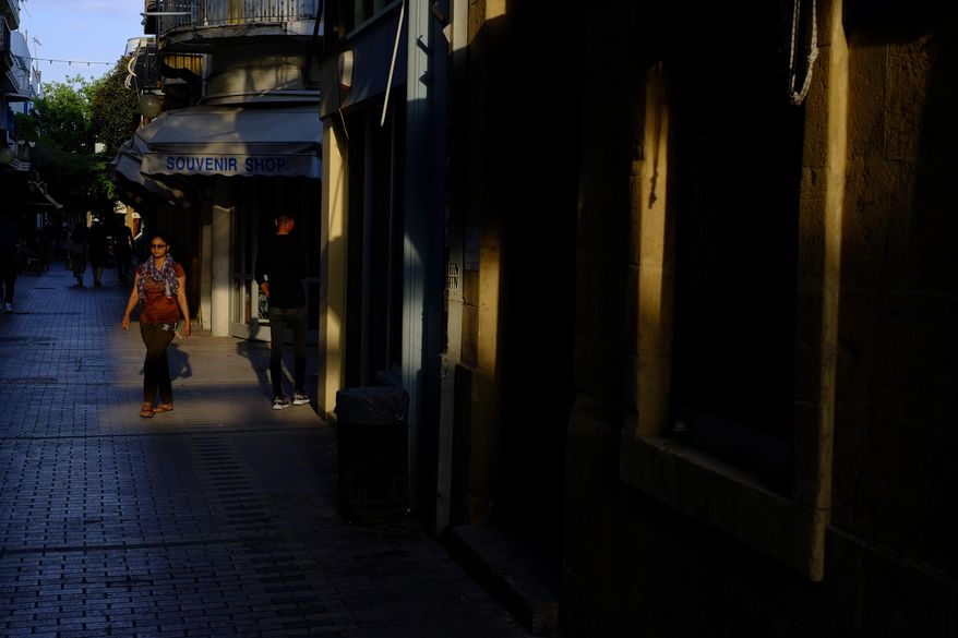 A woman walks past a closed souvenir shop in central capital Nicosia, Cyprus, Wednesday, June 3, 2020. Health Minister Constantinos Ioannou said the third phase of the country's gradual rollback of restrictions will be completed by June 24 instead of July 14. (AP Photo/Petros Karadjias)
