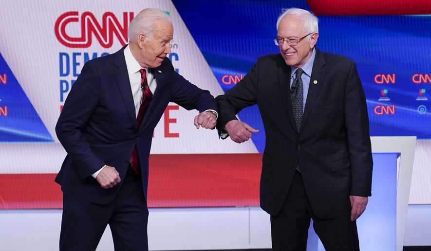 FILE - In this March 15, 2020, file photo, former Vice President Joe Biden, left, and Sen. Bernie Sanders, I-Vt., right, greet one another before they participate in a Democratic presidential primary debate at CNN Studios in Washington. Biden has won the last few delegates he needed to clinch the Democratic nomination for president. (AP Photo/Evan Vucci, File)