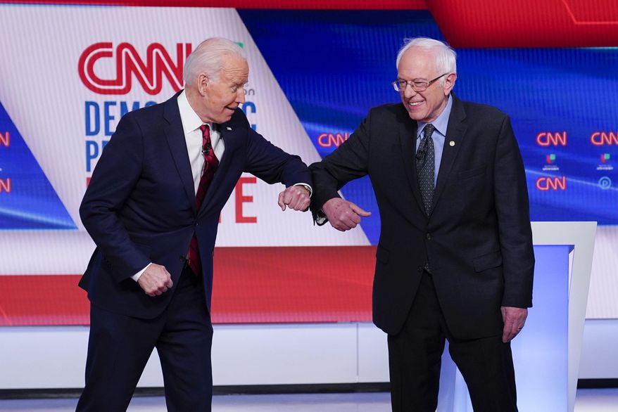 FILE - In this March 15, 2020, file photo, former Vice President Joe Biden, left, and Sen. Bernie Sanders, I-Vt., right, greet one another before they participate in a Democratic presidential primary debate at CNN Studios in Washington. Biden has won the last few delegates he needed to clinch the Democratic nomination for president. (AP Photo/Evan Vucci, File)