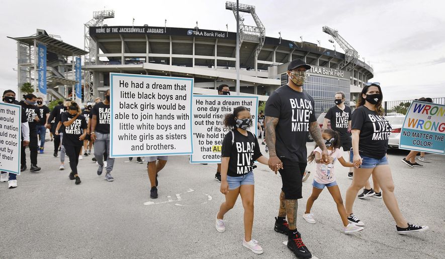 Jacksonville Jaguars assistant defensive line coach Dwayne Stukes walks with his family near the front of the line of players, staff and family members as they start a march from TIAA Bank Field to the Jacksonville Sheriff's office headquarters, Friday morning, June 5, 2020, in Jacksonville, Fla., to protest against inequality and police brutality. (Bob Self/The Florida Times-Union via AP)