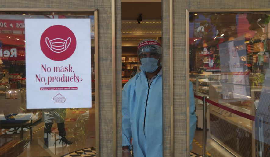 An Indian security personnel wearing protective gear stands by the entrance of a sweet shop in Hyderabad, India, Friday, June 5, 2020. The more than two-month-old lockdown is now largely being enforced only in high-risk areas, known as containment zones. The government has partially restored train service and domestic flights and allowed the reopening of shops and manufacturing. (AP Photo/Mahesh Kumar A.)
