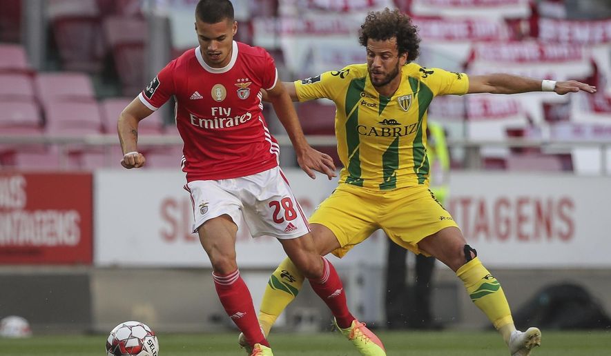 Benfica's player Julian Weigl, left, vies for the ball with Tondela's Joao Pedro during a Portuguese League soccer match between Benfica and Tondela in Lisbon, Portugal, Thursday, June 4, 2020. The Portuguese League soccer matches resumed Wednesday without spectators because of the coronavirus pandemic. (Tiago Petinga/Pool via AP)
