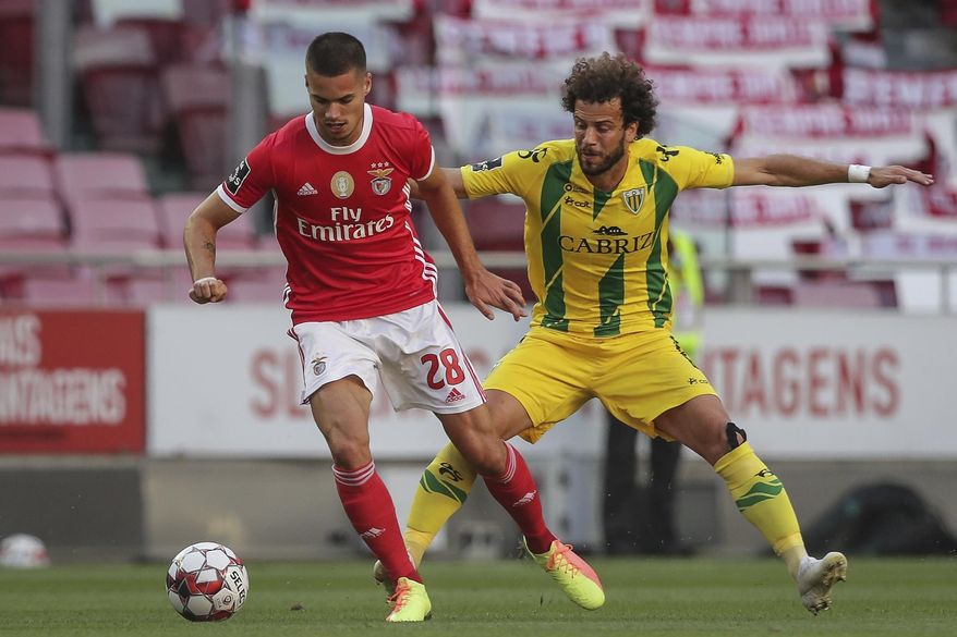 Benfica's player Julian Weigl, left, vies for the ball with Tondela's Joao Pedro during a Portuguese League soccer match between Benfica and Tondela in Lisbon, Portugal, Thursday, June 4, 2020. The Portuguese League soccer matches resumed Wednesday without spectators because of the coronavirus pandemic. (Tiago Petinga/Pool via AP)