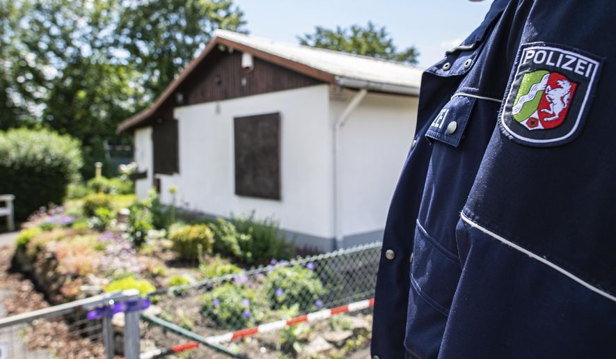 During the investigation of serious sexual abuse of children, a police officer is standing in front of the arbour where the presumed main perpetrator placed parts of his server system, in Muenster, Germany, Saturdau, June 6, 2020. The investigators found hard disks and video cameras among other things. (Guido Kirchner/dpa via AP)