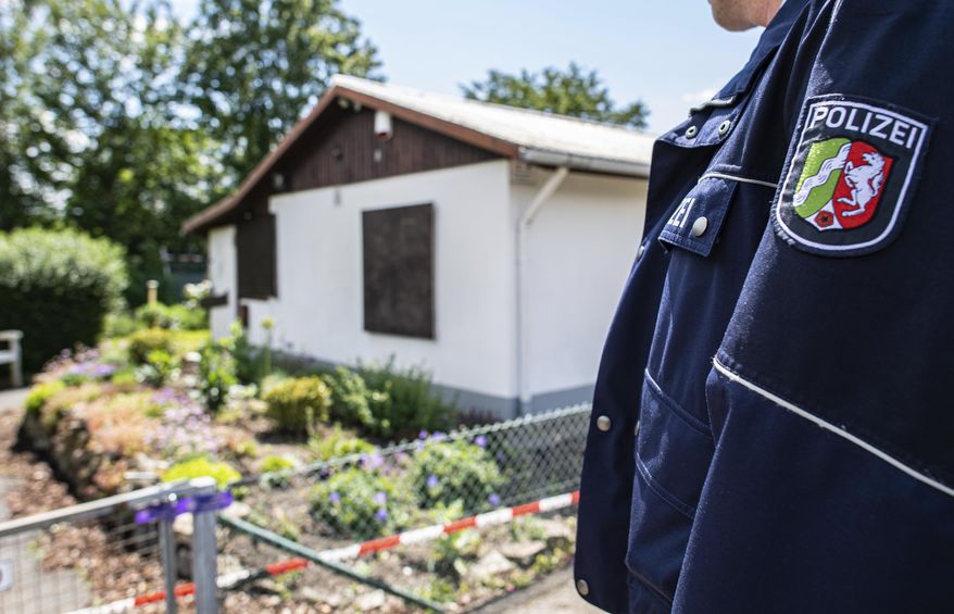 During the investigation of serious sexual abuse of children, a police officer is standing in front of the arbour where the presumed main perpetrator placed parts of his server system, in Muenster, Germany, Saturdau, June 6, 2020. The investigators found hard disks and video cameras among other things. (Guido Kirchner/dpa via AP)